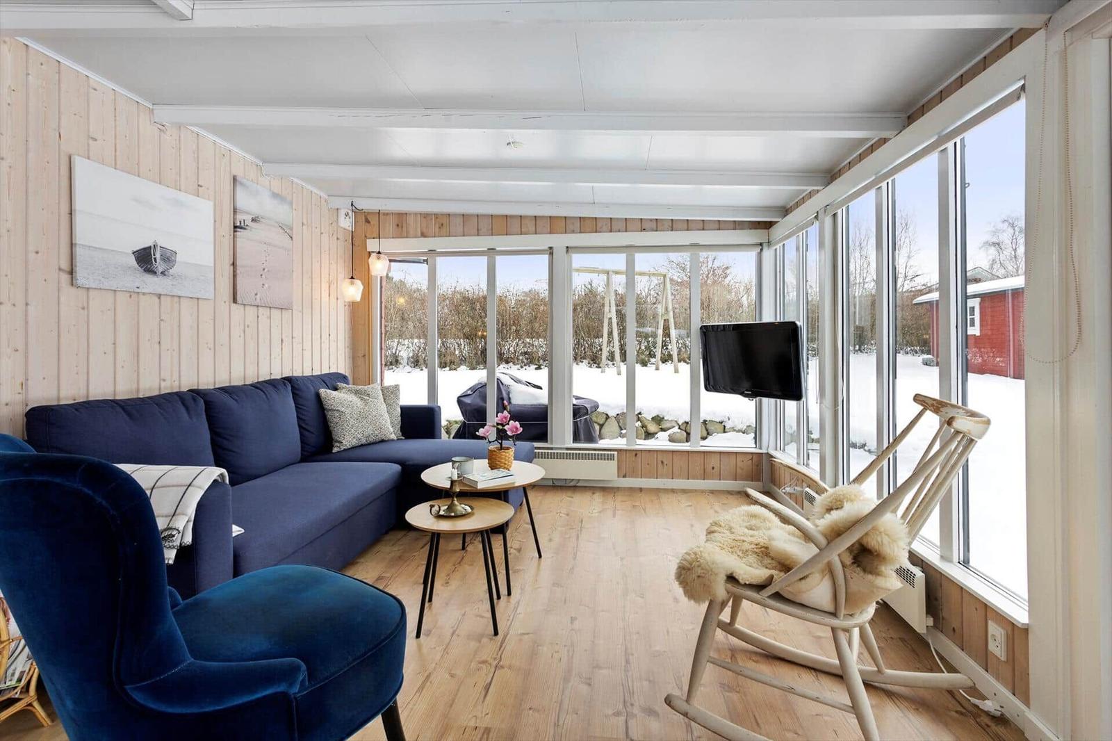 Living room with blue sofa, wooden floor, and large windows to the garden.