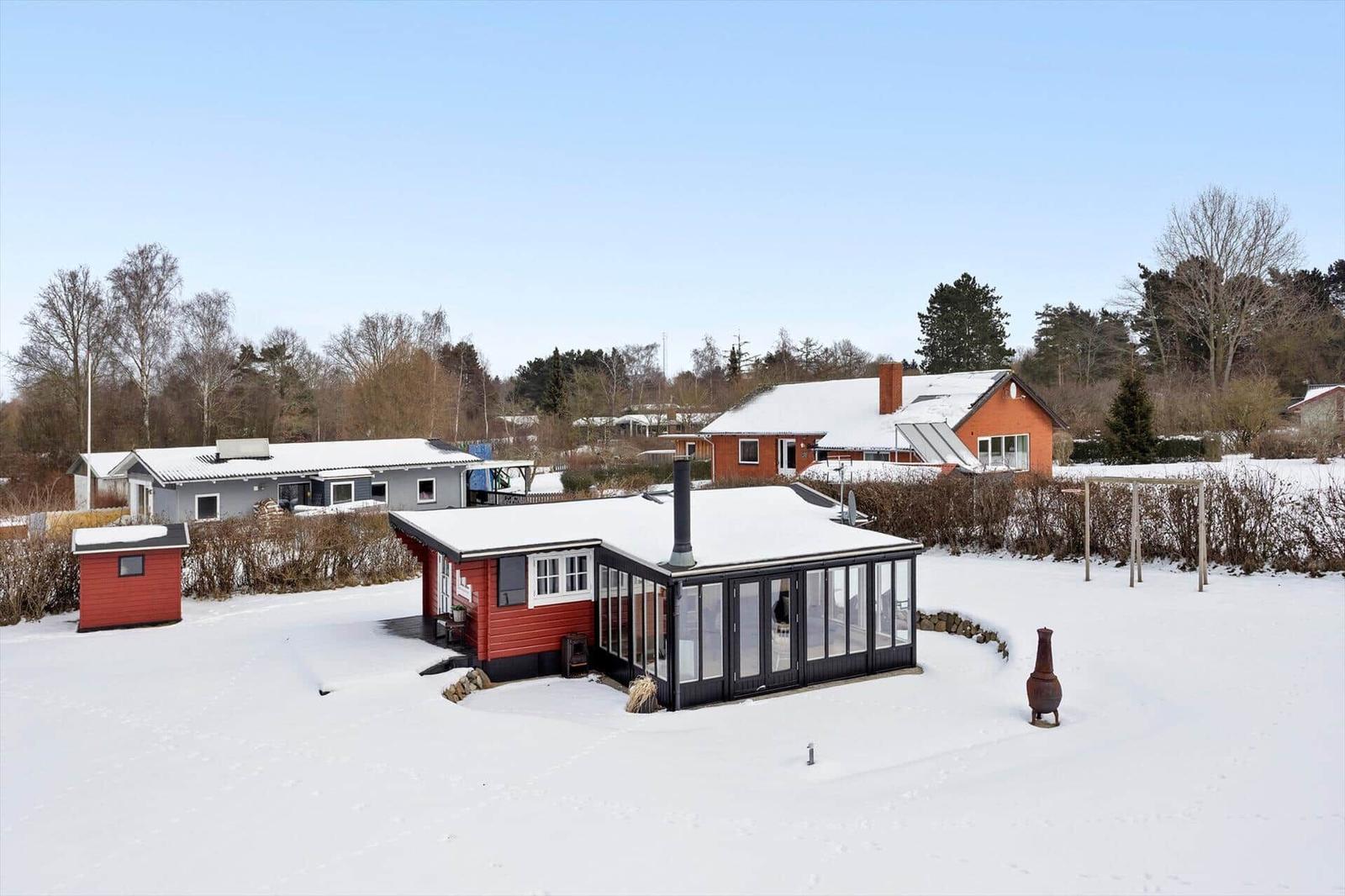 Snow-covered vacation homes with glass conservatory and garden.