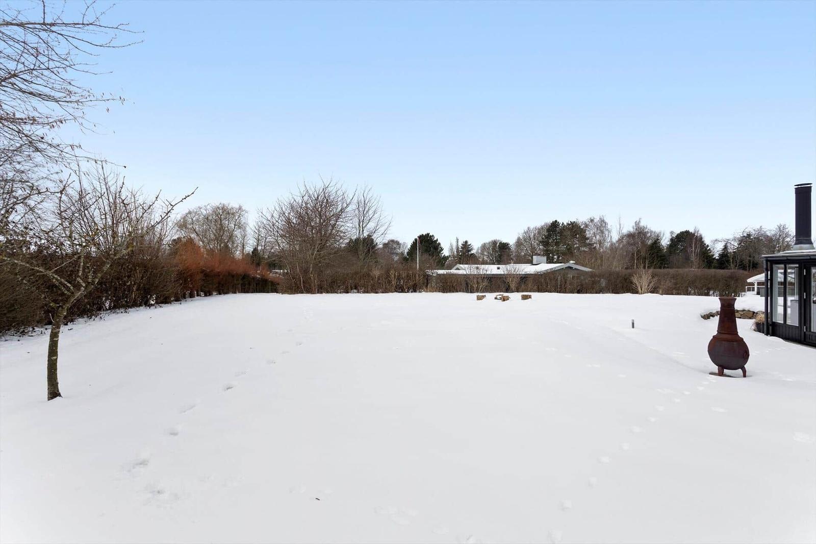 Snow-covered garden with wood-burning stove and view of the house.