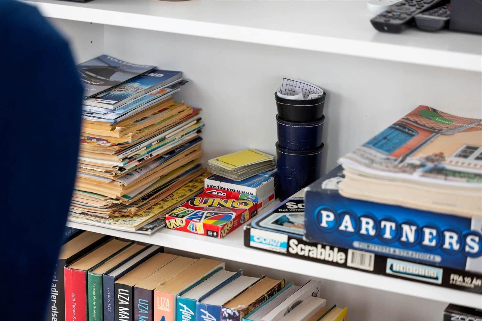 Shelf with games, magazines, and books.
