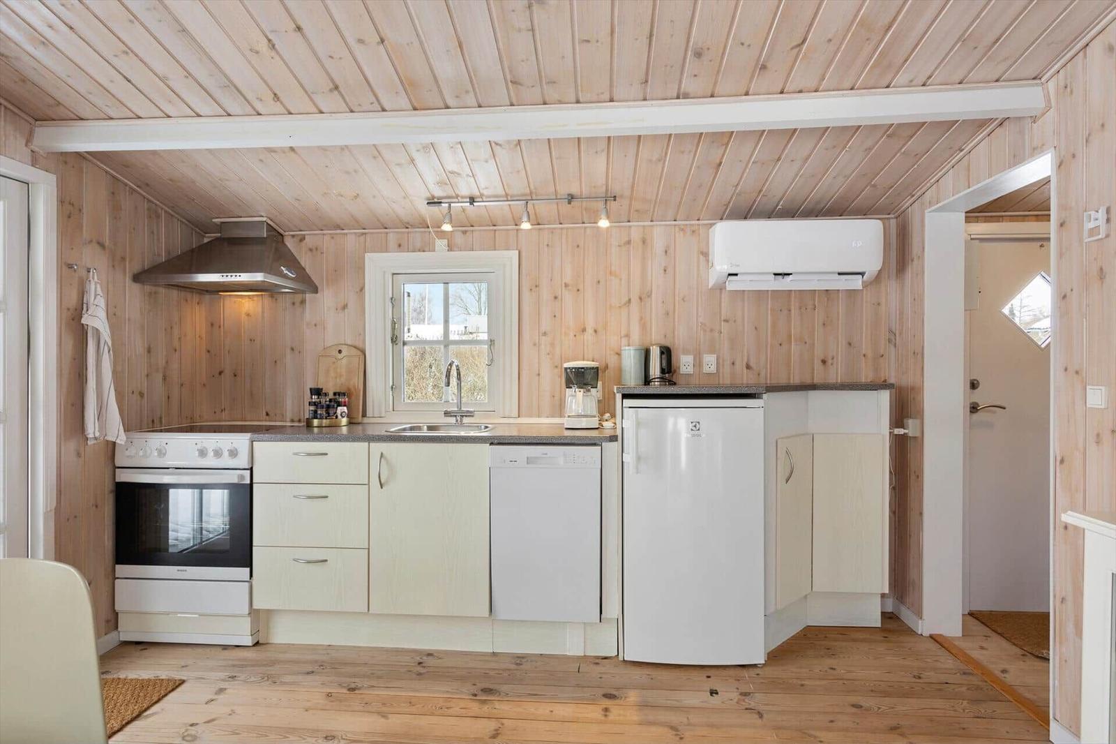 Kitchen with wooden walls, sink, refrigerator, and stove.