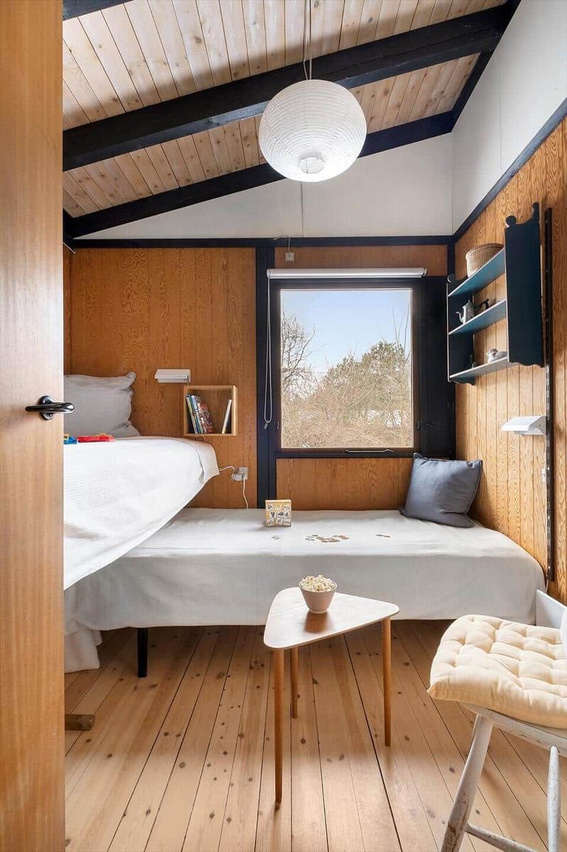 Bedroom with wooden floor, bed, window, and small table.