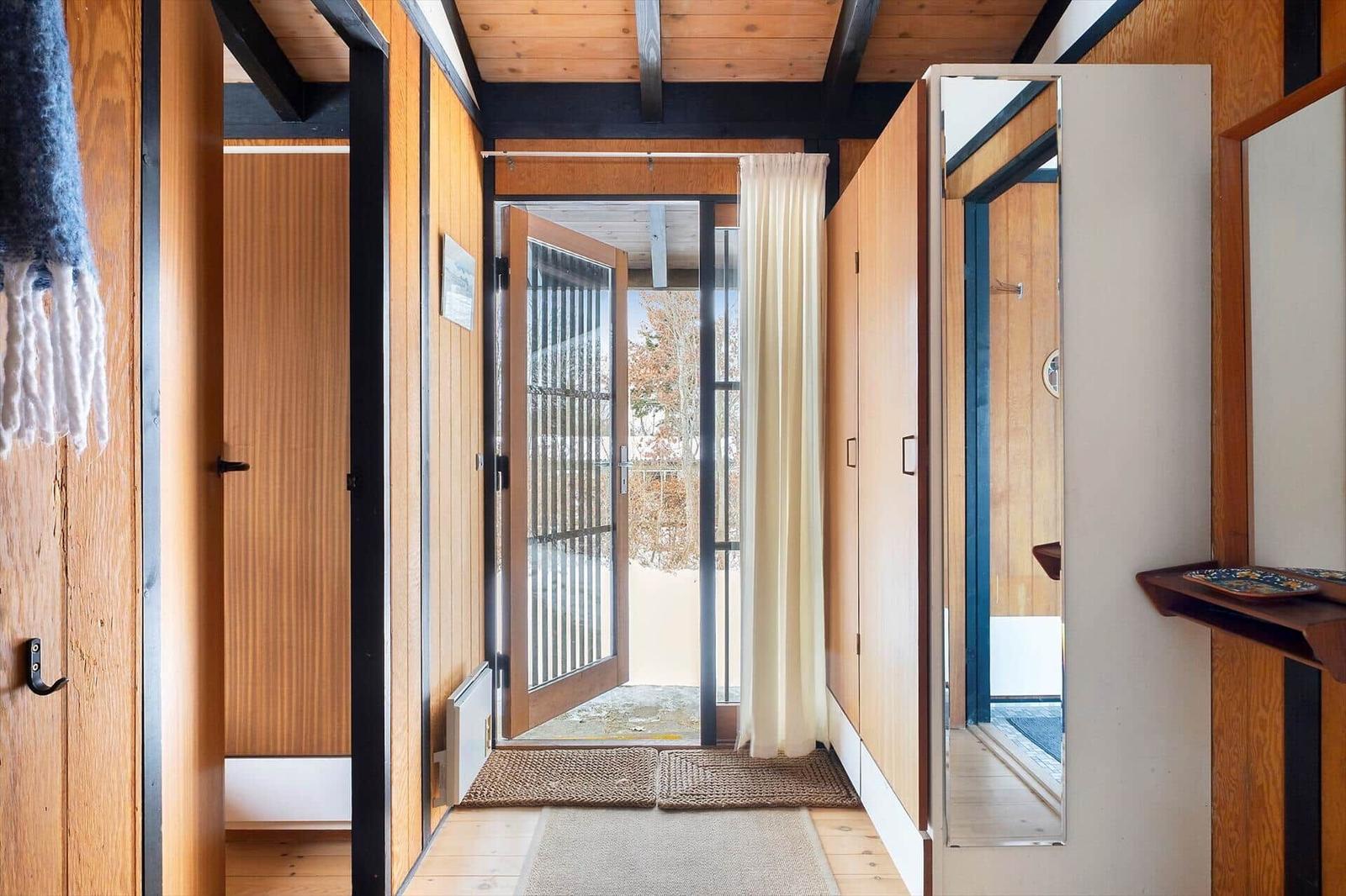 Entrance with wooden walls, door to the outside, and mirror on the wall.