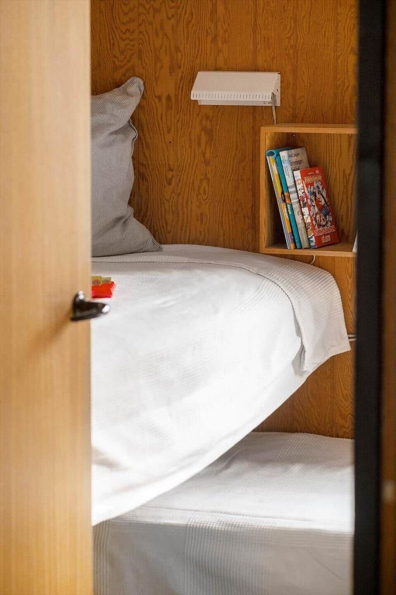 A bed with white bedding, pillows, and a bookshelf on the wall.