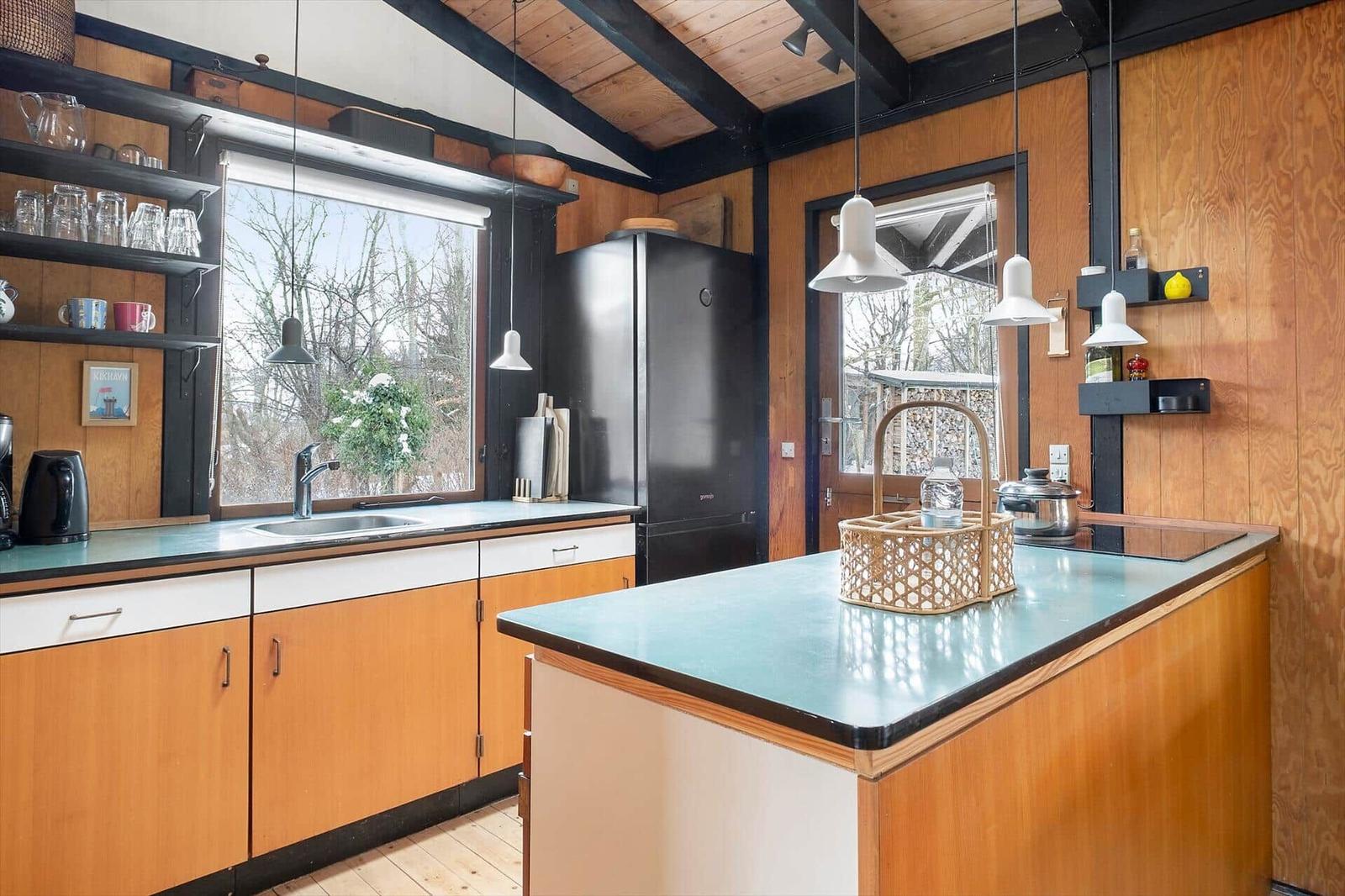 Kitchen with wooden walls, kitchen island, and view of outdoor area.