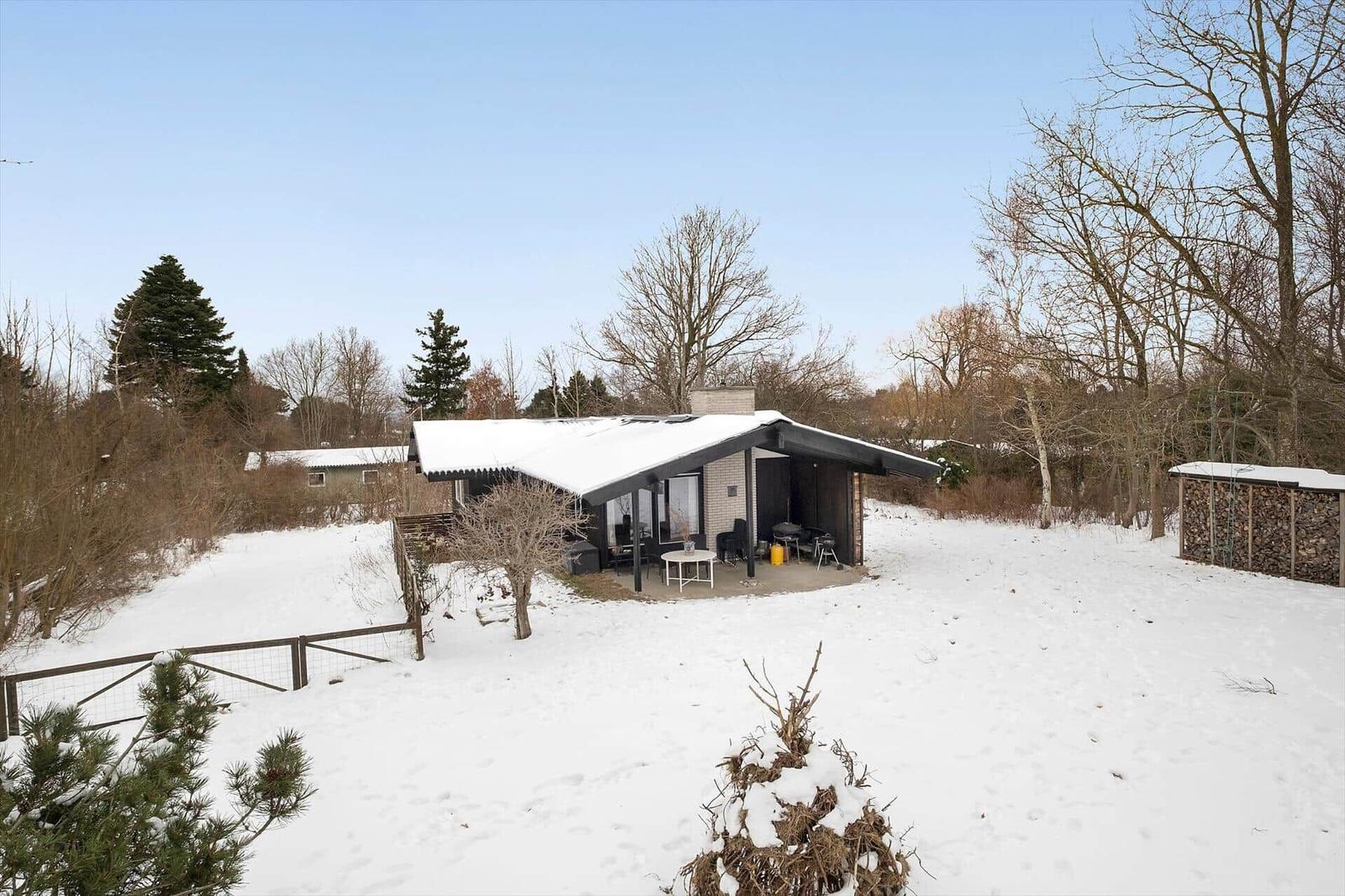 Snow-covered garden with modern house and terrace.