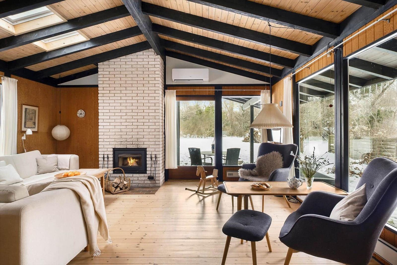 Living room with fireplace, wooden floor, and large window view of the garden.