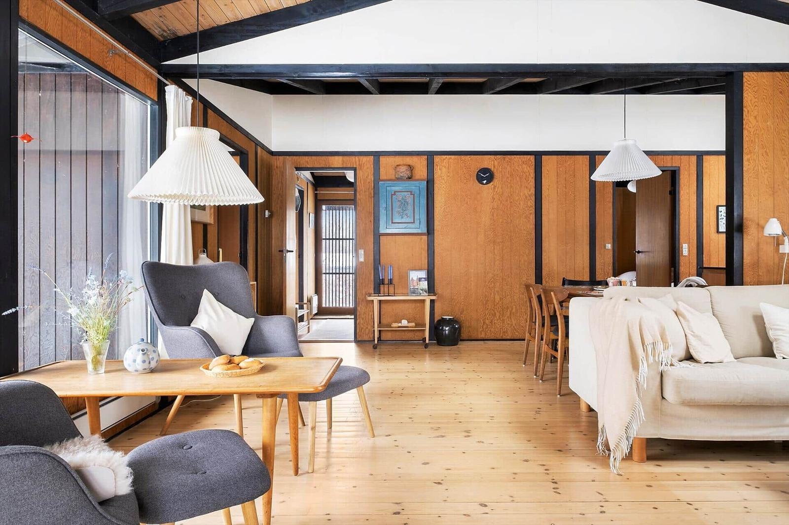 Living and dining area with wooden floor, sofa, chairs, and table.