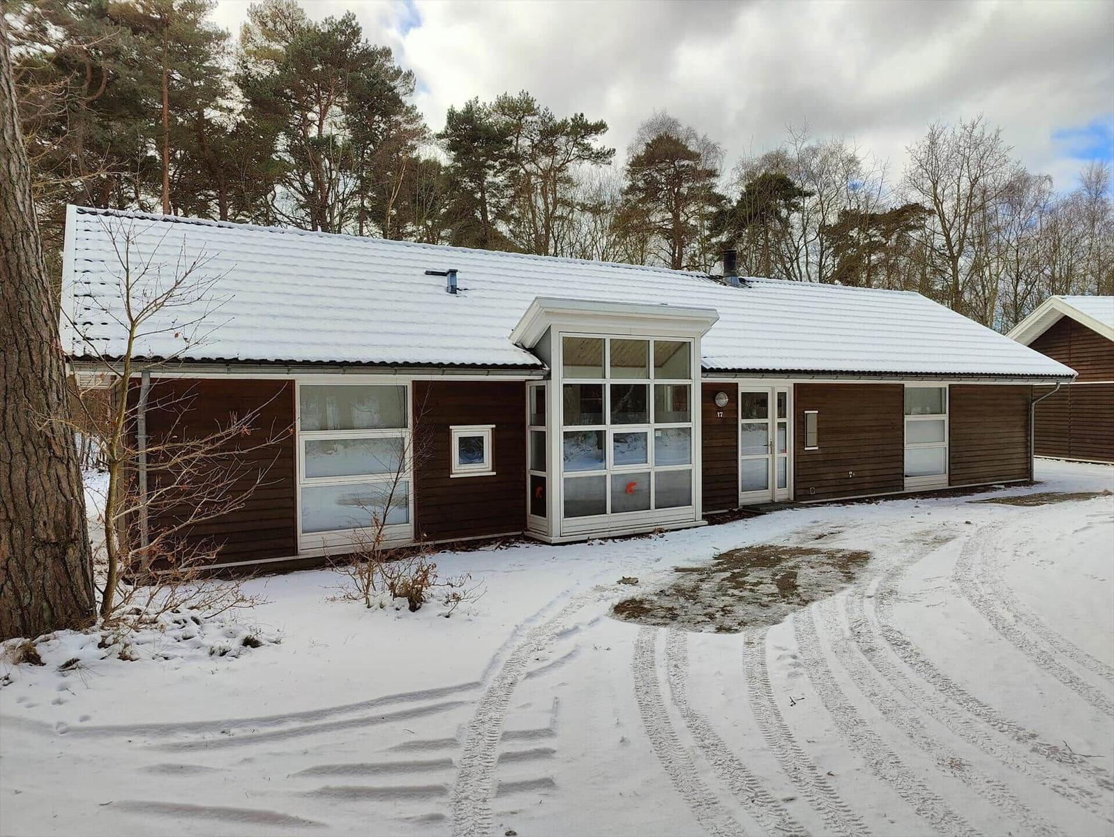 House with snow-covered roof and wooden facade in the forest