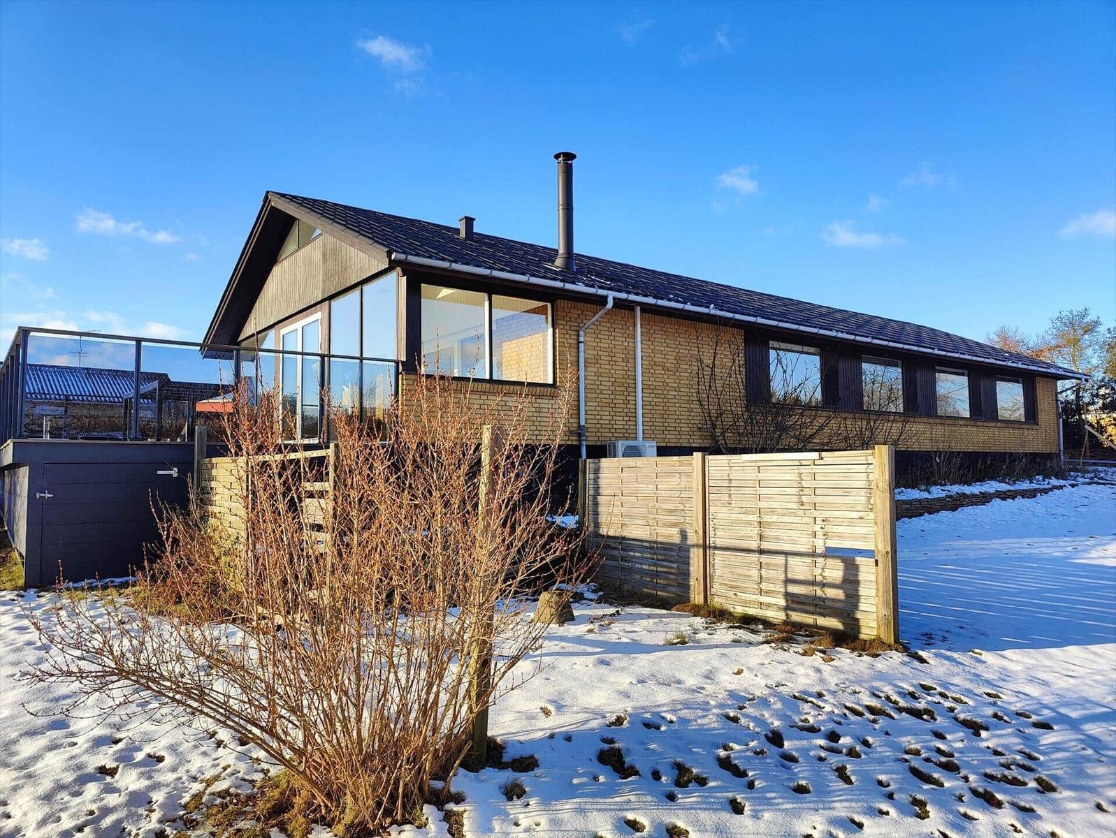 Modern house with snow-covered grounds and wooden fence