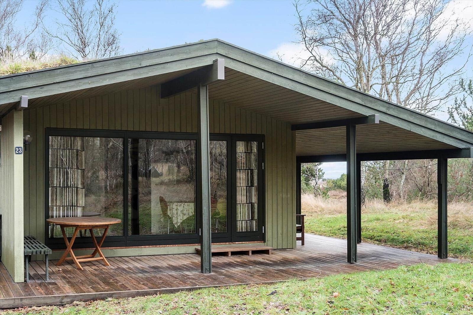 Moderne Hütte mit Holzterrasse und großem Fenster. Grün-dach und freier Blick in die Natur.