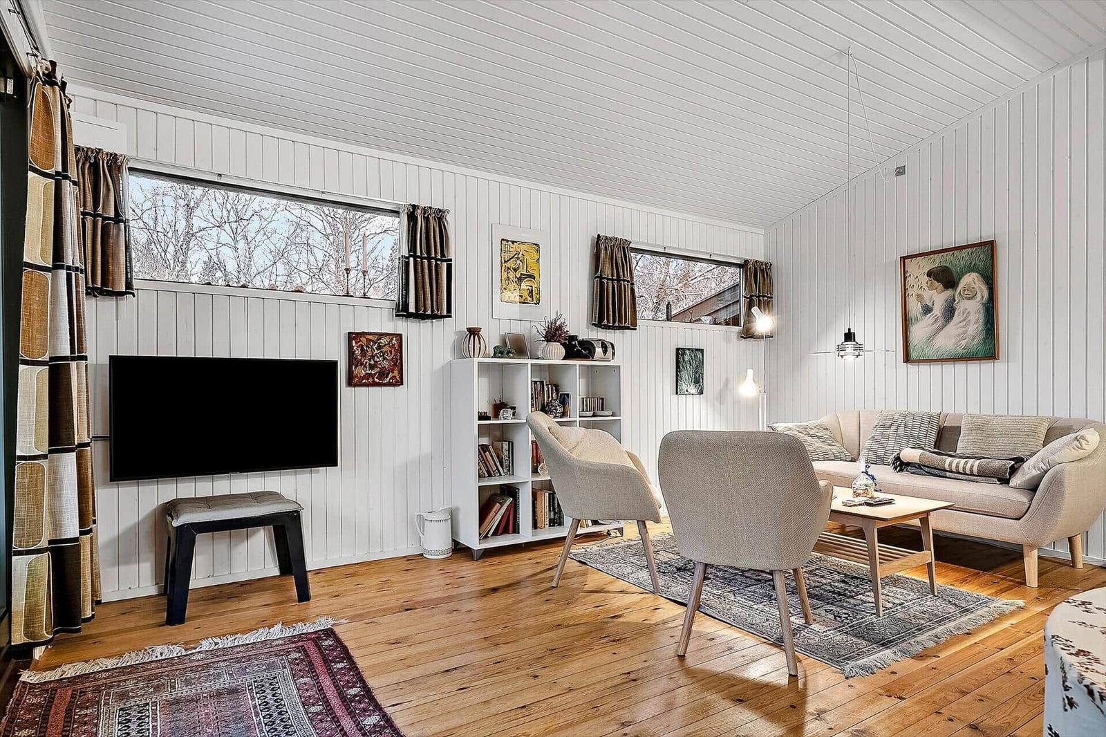 Wohnzimmer mit Sofa, Stühlen, Fernseher und Holzboden.