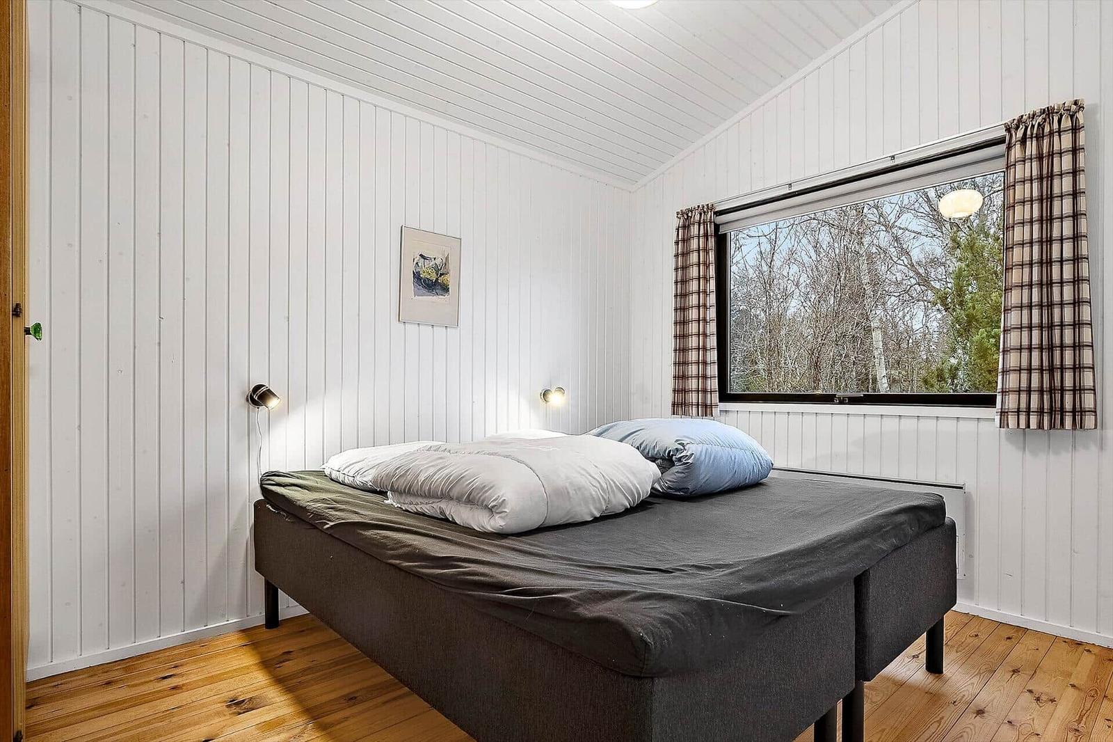 Schlafzimmer mit Bett, Fenster und Holzboden.