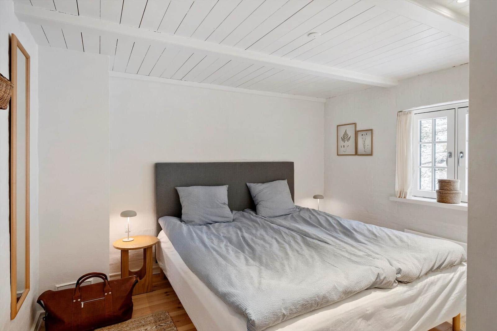 Schlafzimmer mit Bett, Fenster und Nachttisch.