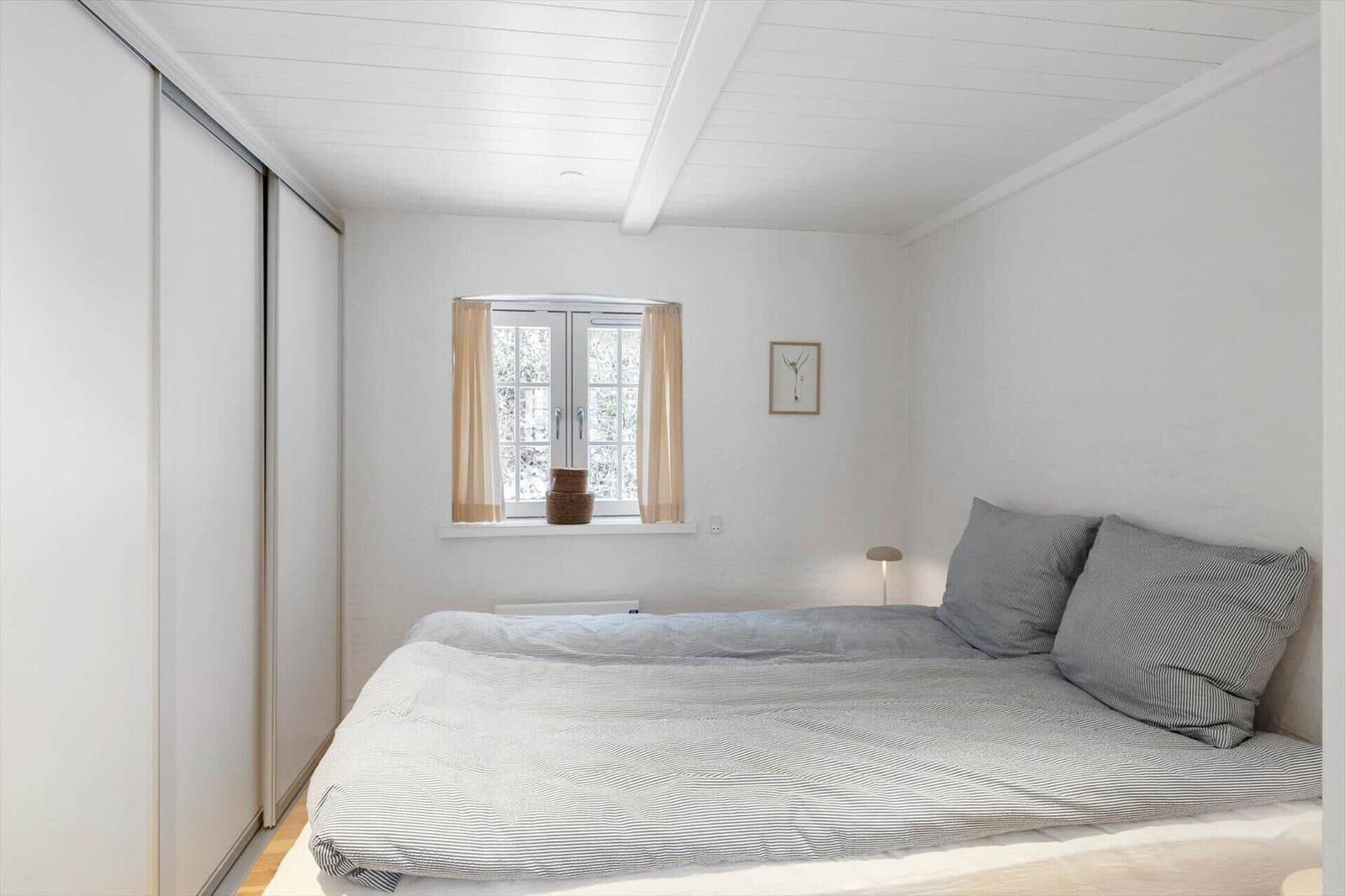 Schlafzimmer mit Bett, Fenster und Schiebetüren.