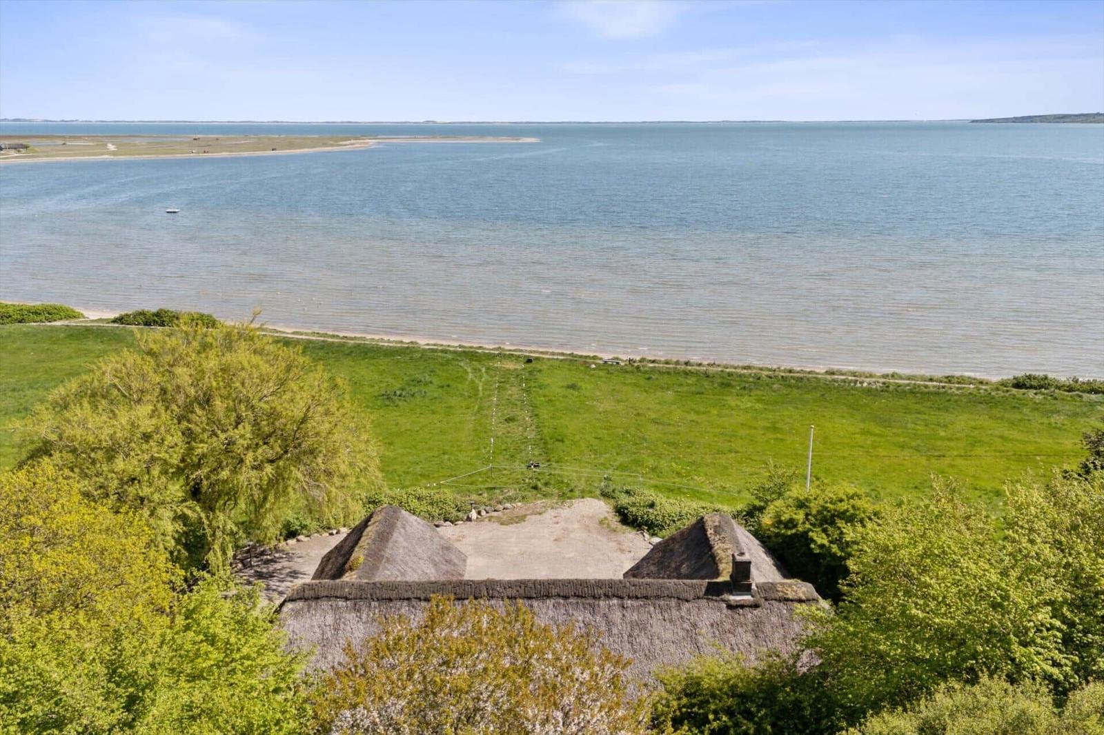 Haus mit Strohdach, Grünfläche und Blick auf Wasser