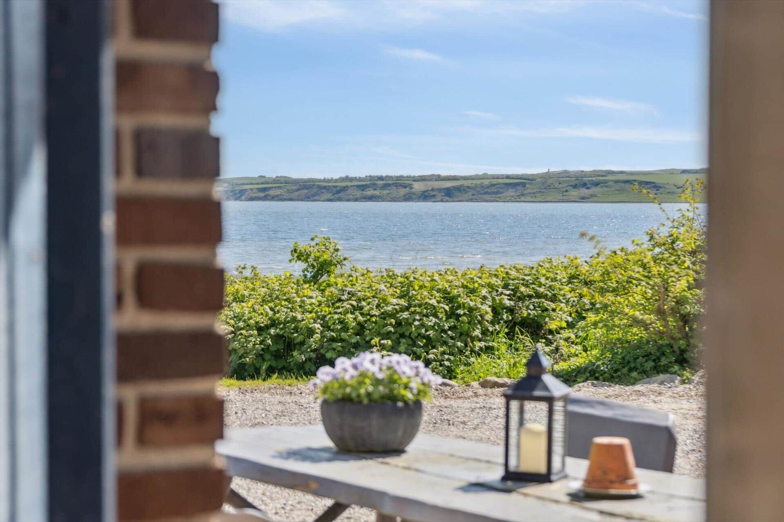 Blick auf einen See mit grüner Vegetation und einem Steinbrunnen im Vordergrund.