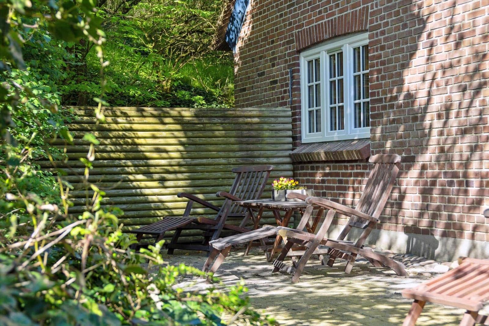 Hinterhof mit Holzstühlen, Tisch und Blumen vor Backsteinhaus