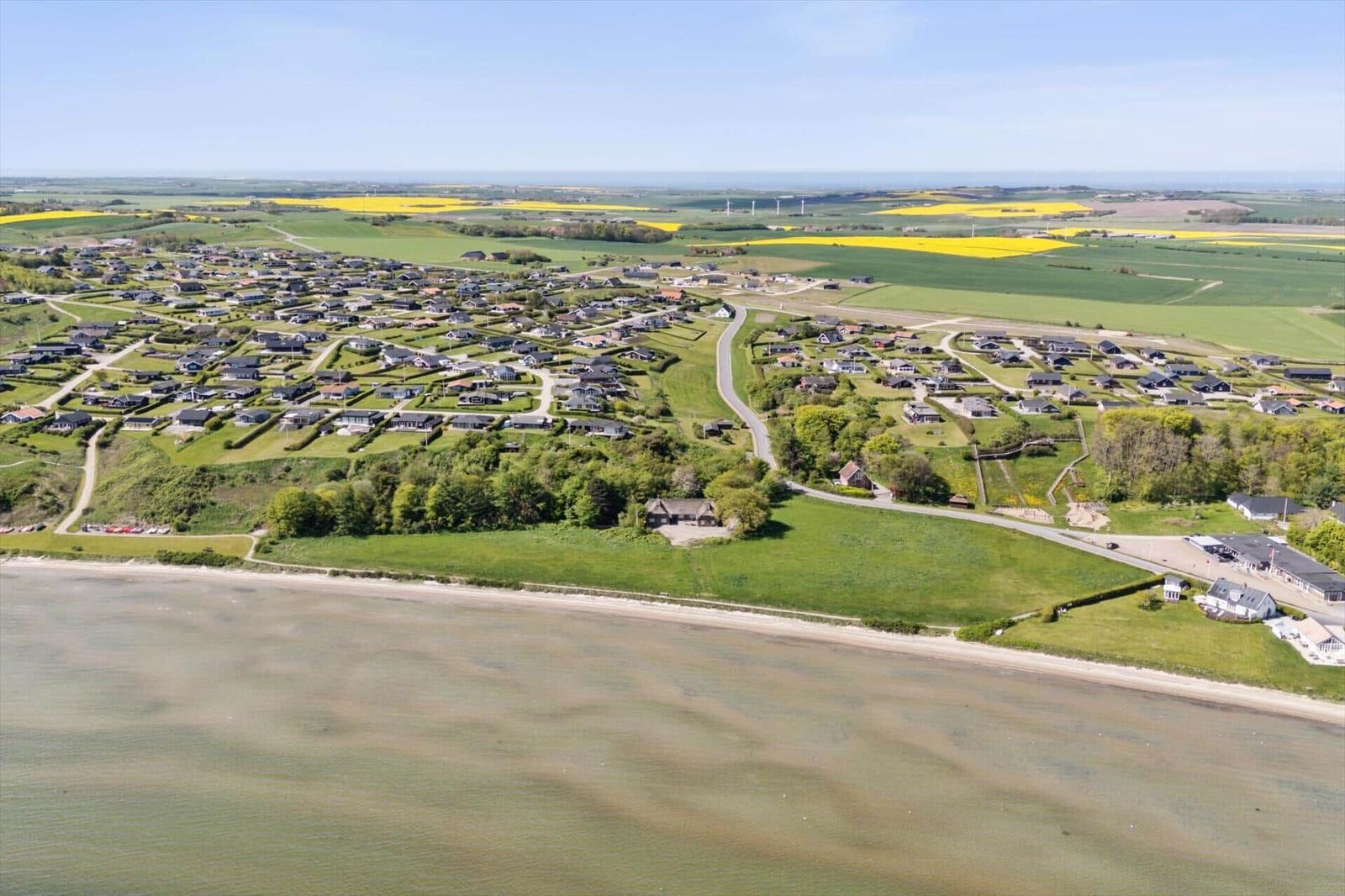 Aeriale Aufnahme einer Küstenlandschaft mit Häusern, Feldern und Meer.