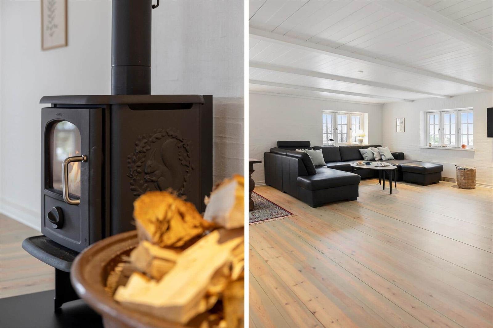 Ein Kaminofen mit Brennholz und ein großes Wohnzimmer mit Ledersofa und Holzboden.