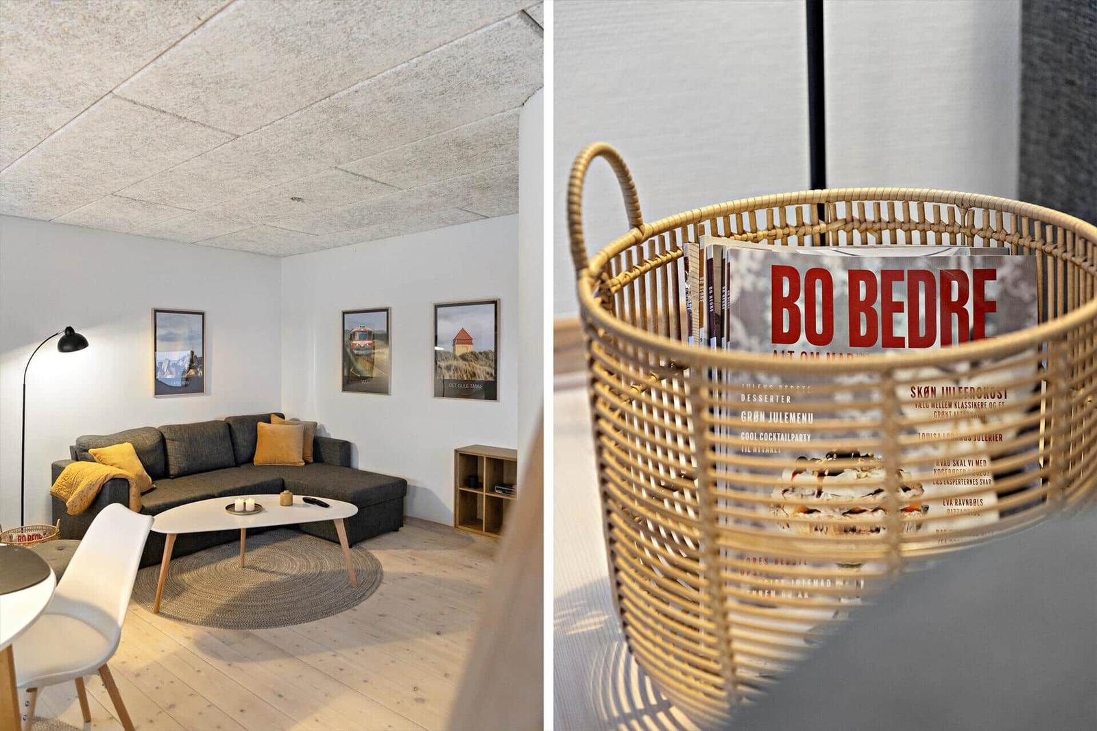 Wohnzimmer mit Sofa, Couchtisch und Wandbildern. Magazine in einem Korb.