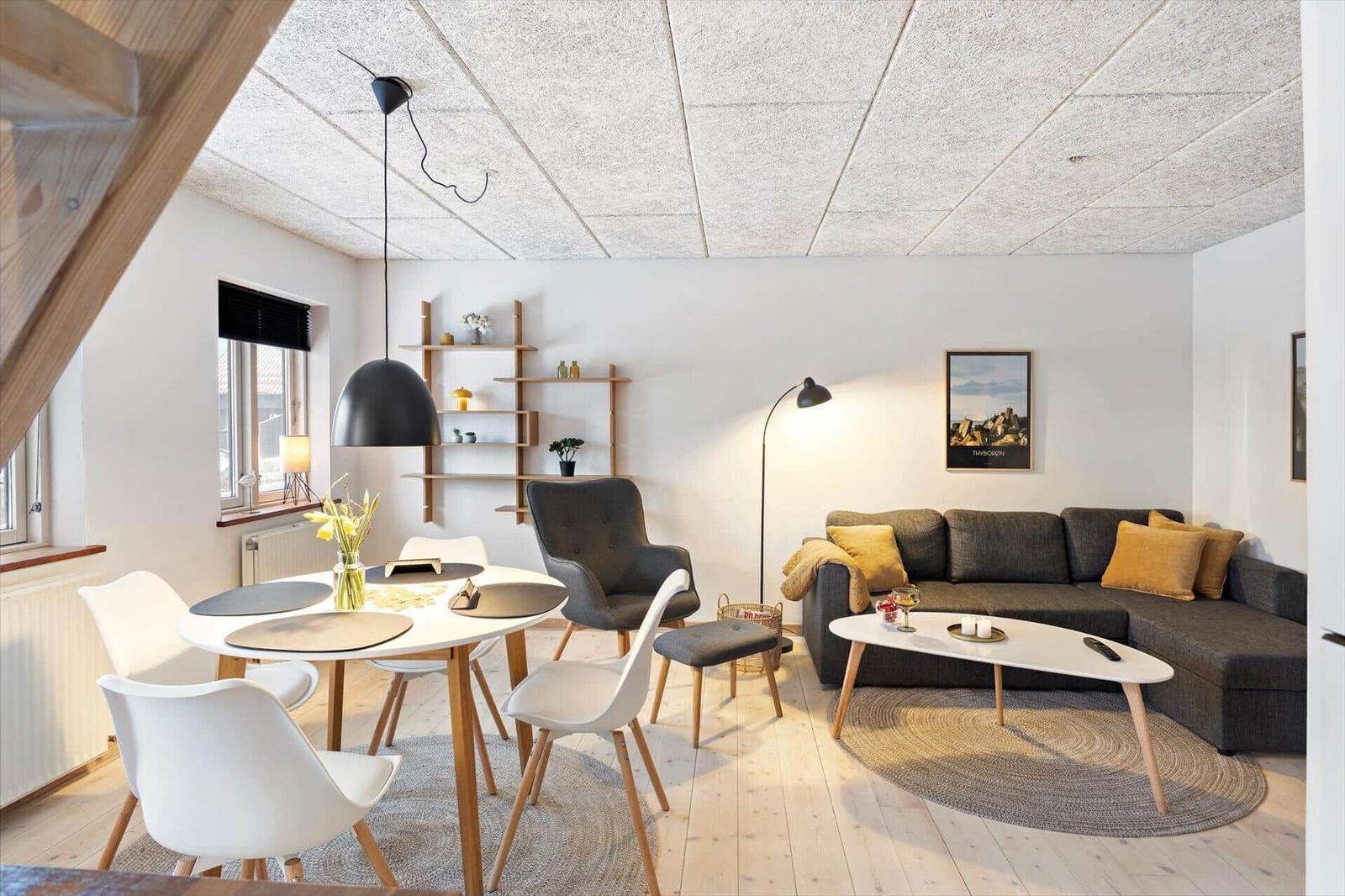 Wohn- und Essbereich mit Sofa, Tisch und Stühlen. Holzboden und heller Raum.