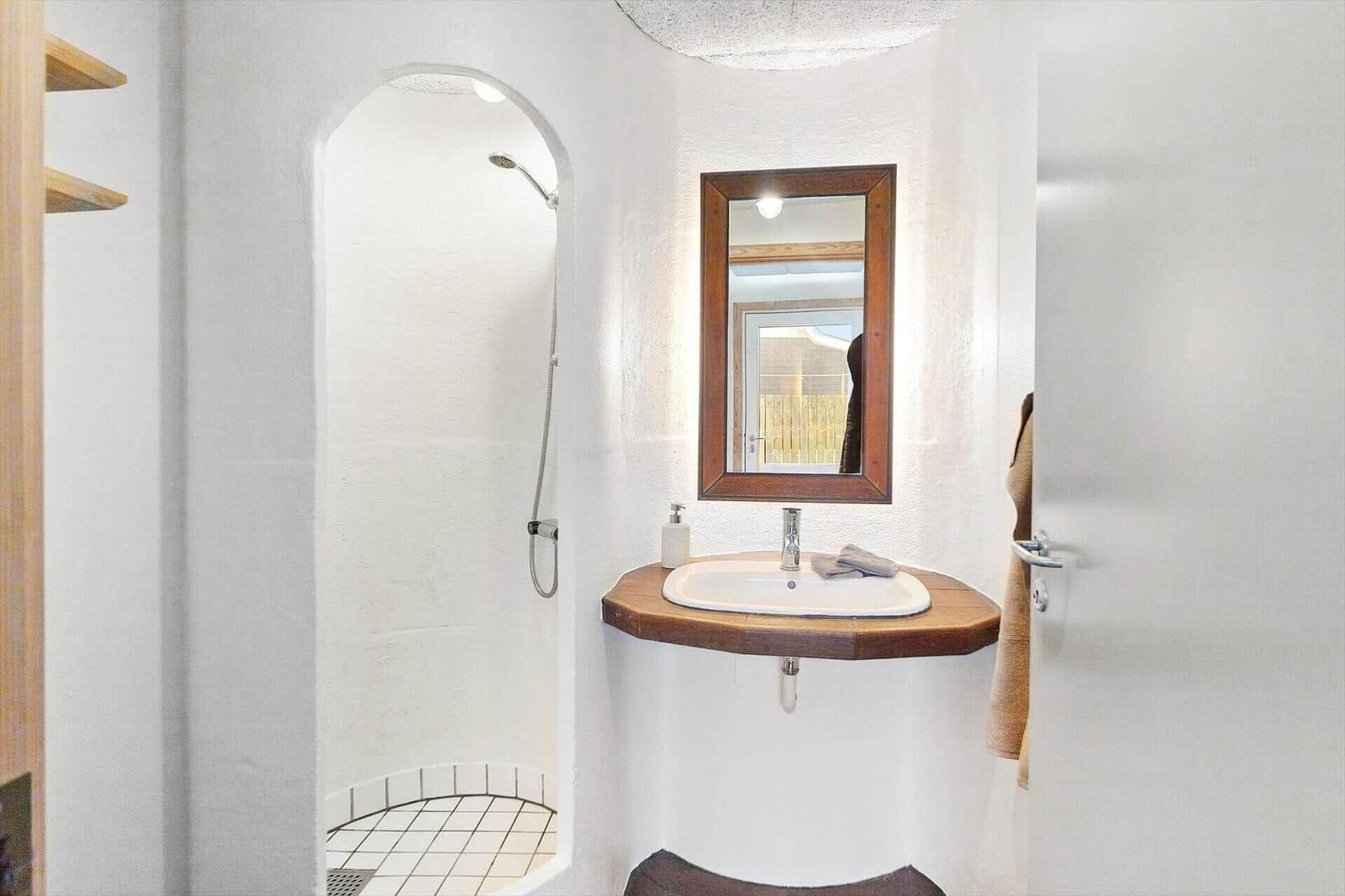 Badezimmer mit Dusche, Waschbecken und Spiegel.