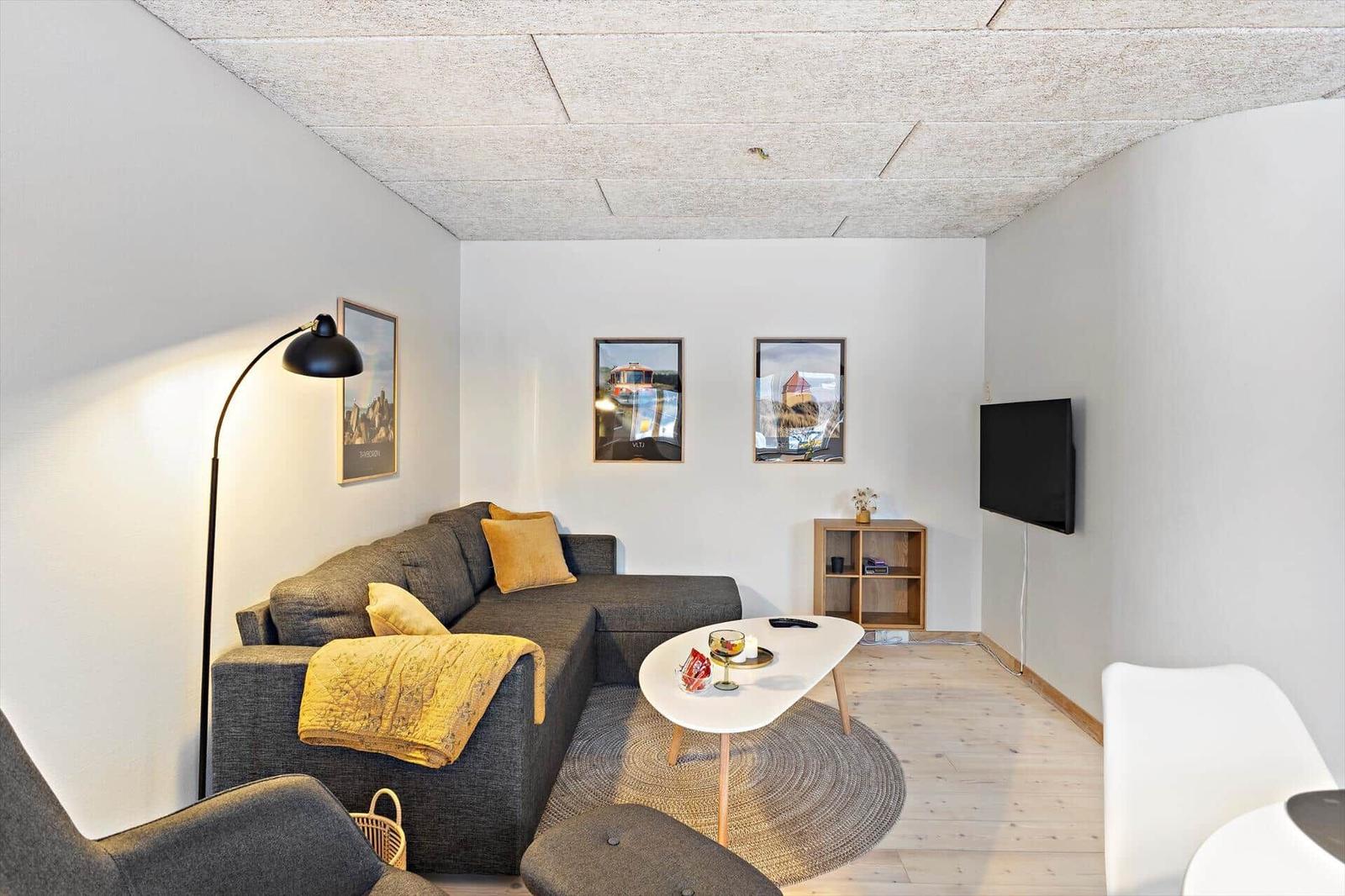 Wohnzimmer mit Sofa, Tisch und Fernseher an der Wand.