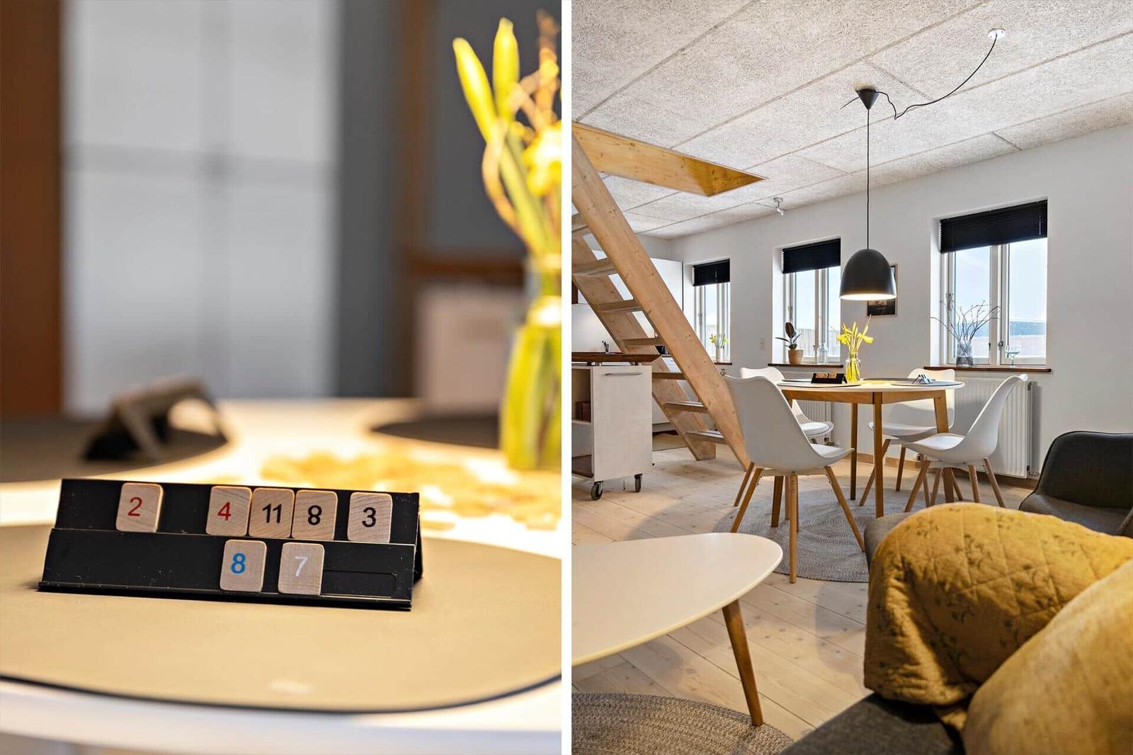 Tisch mit Zahlenblock und gelben Blumen. Wohnraum mit Tisch, Stühlen und Treppe.