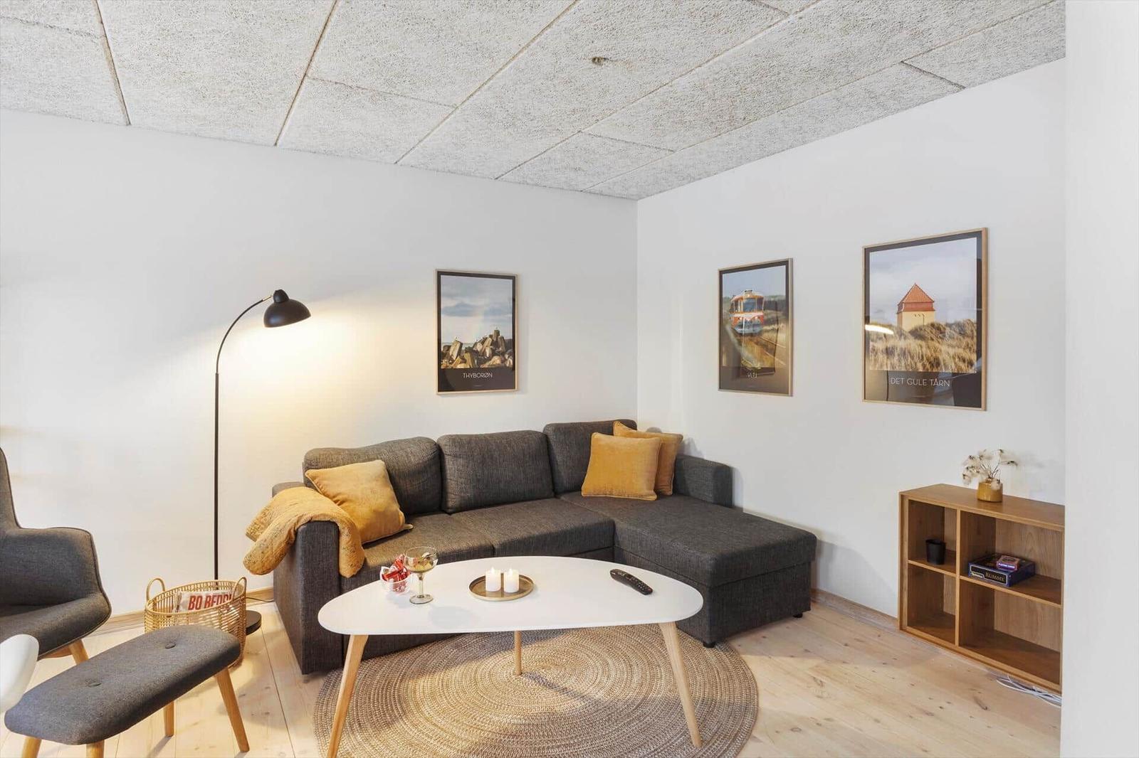 Ein Wohnzimmer mit grauem Sofa, weißem Tisch und Holzboden.