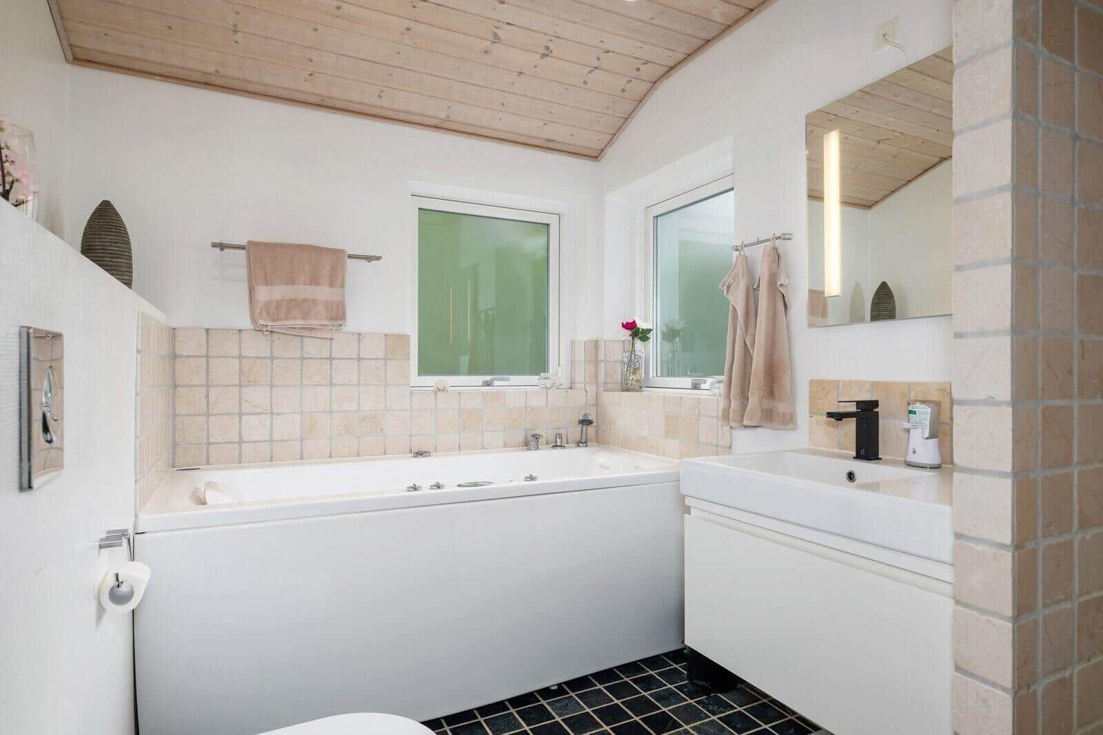 Bathroom with bathtub, sink, and wooden ceiling.