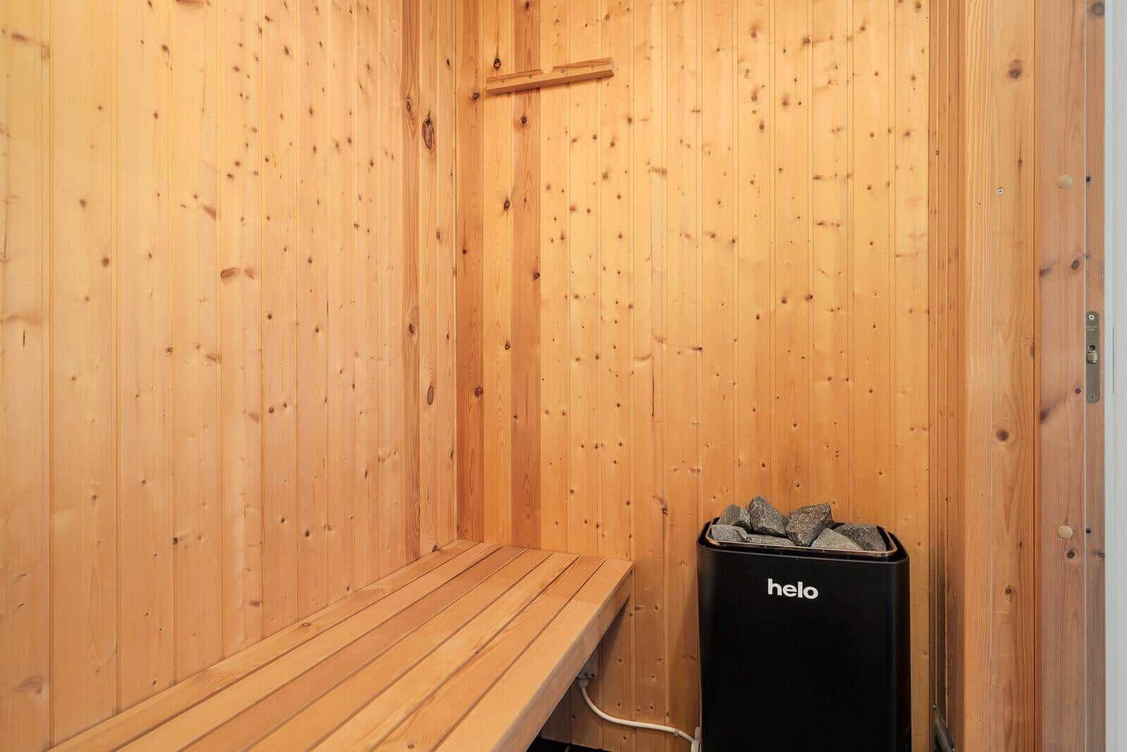Sauna with wooden walls and bench. Heater with stone container.