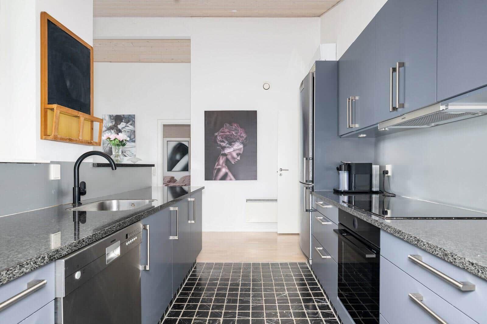 Modern kitchen with gray cabinets, black countertop, and stainless steel appliances.