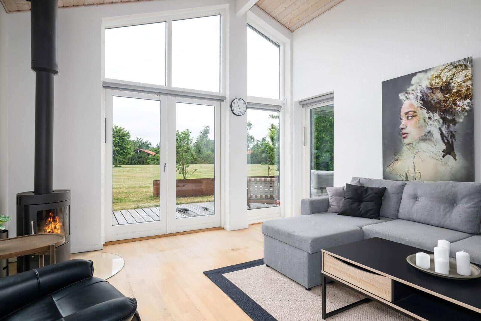 Living room with gray sofa, fireplace, and large windows to terrace.