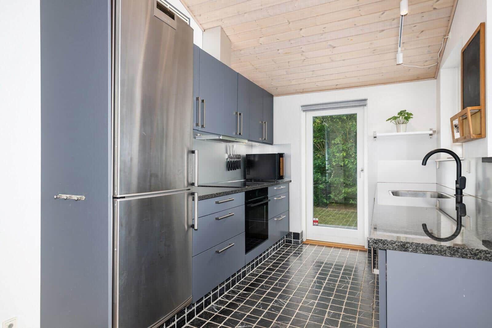 Kitchen with gray cabinets, stainless steel refrigerator, and black sink.