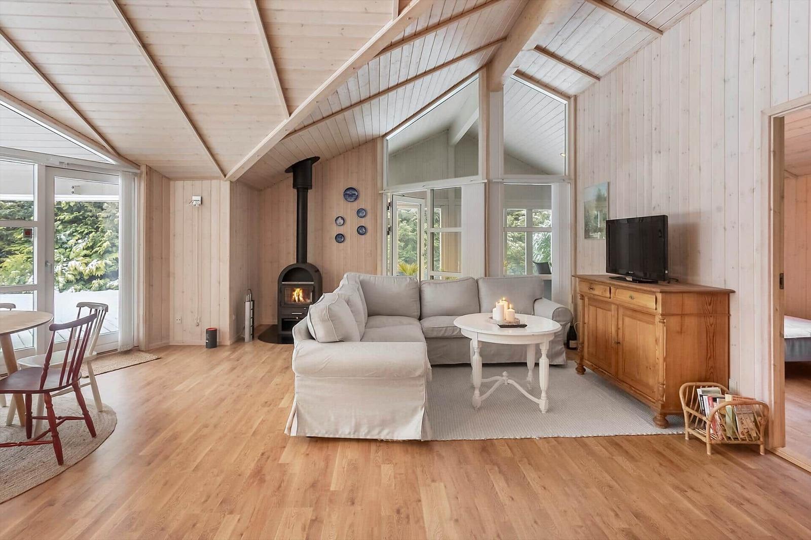 Living room with wooden ceiling, sofa, fireplace, and TV.