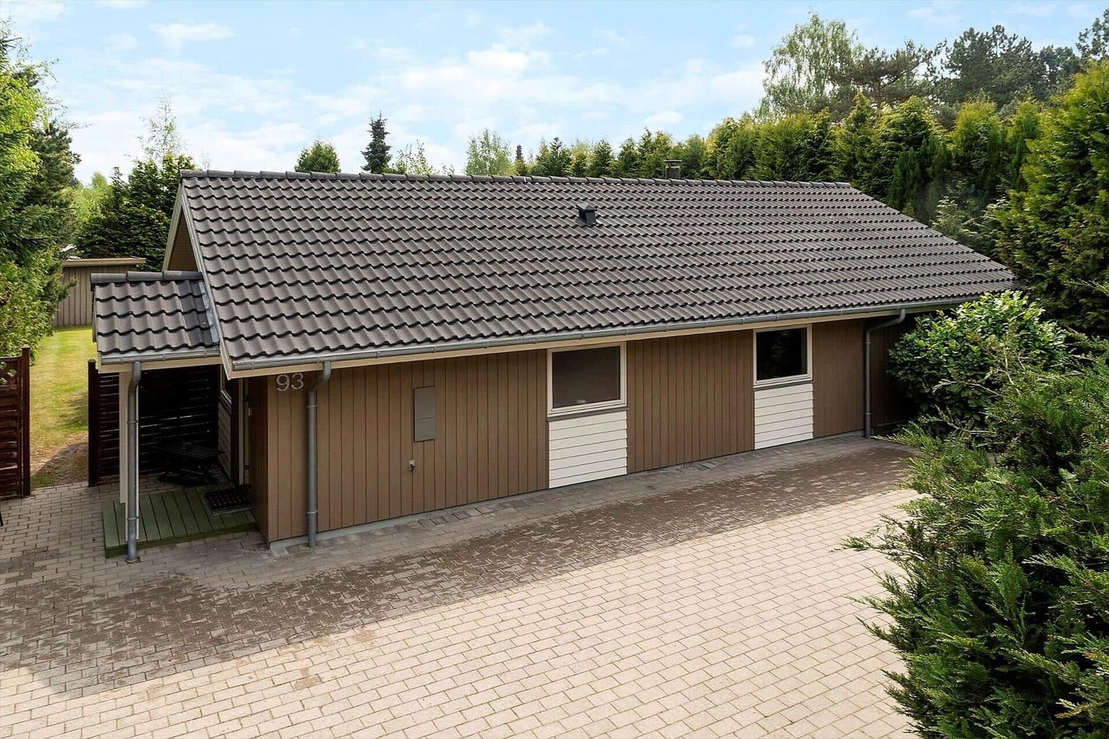 Single-family house with wooden siding and tiled roof. Surrounded by greenery and trees.