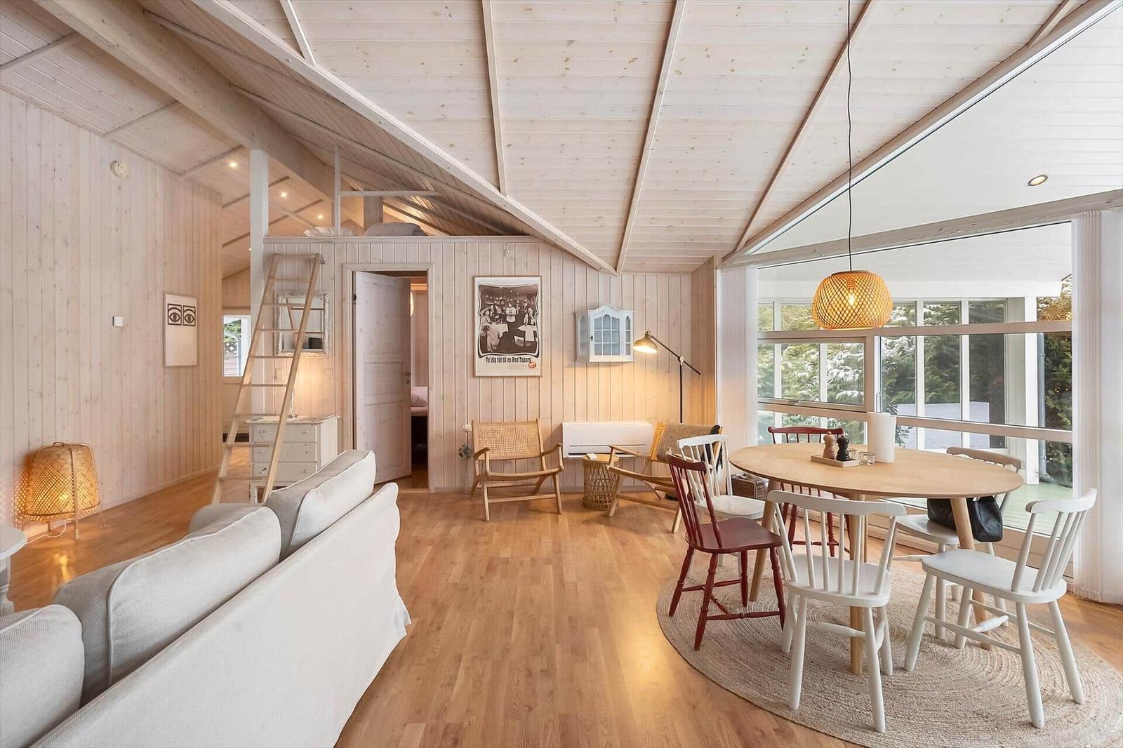 Living area with dining table, sofa, and sleeping area above