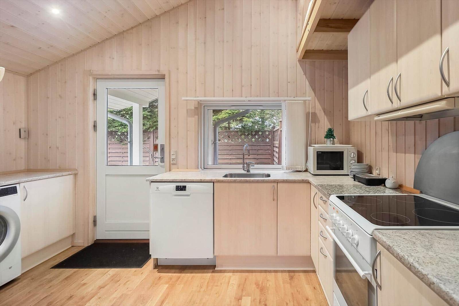Kitchen with sink, stove, microwave, and washing machine.