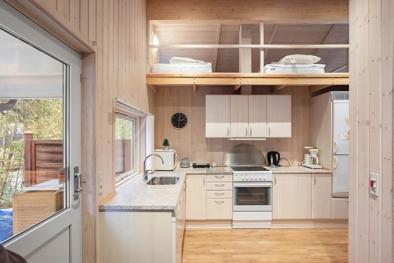 Kitchen with countertop, sink, stove, and refrigerator. Above sleeping area with mattresses.