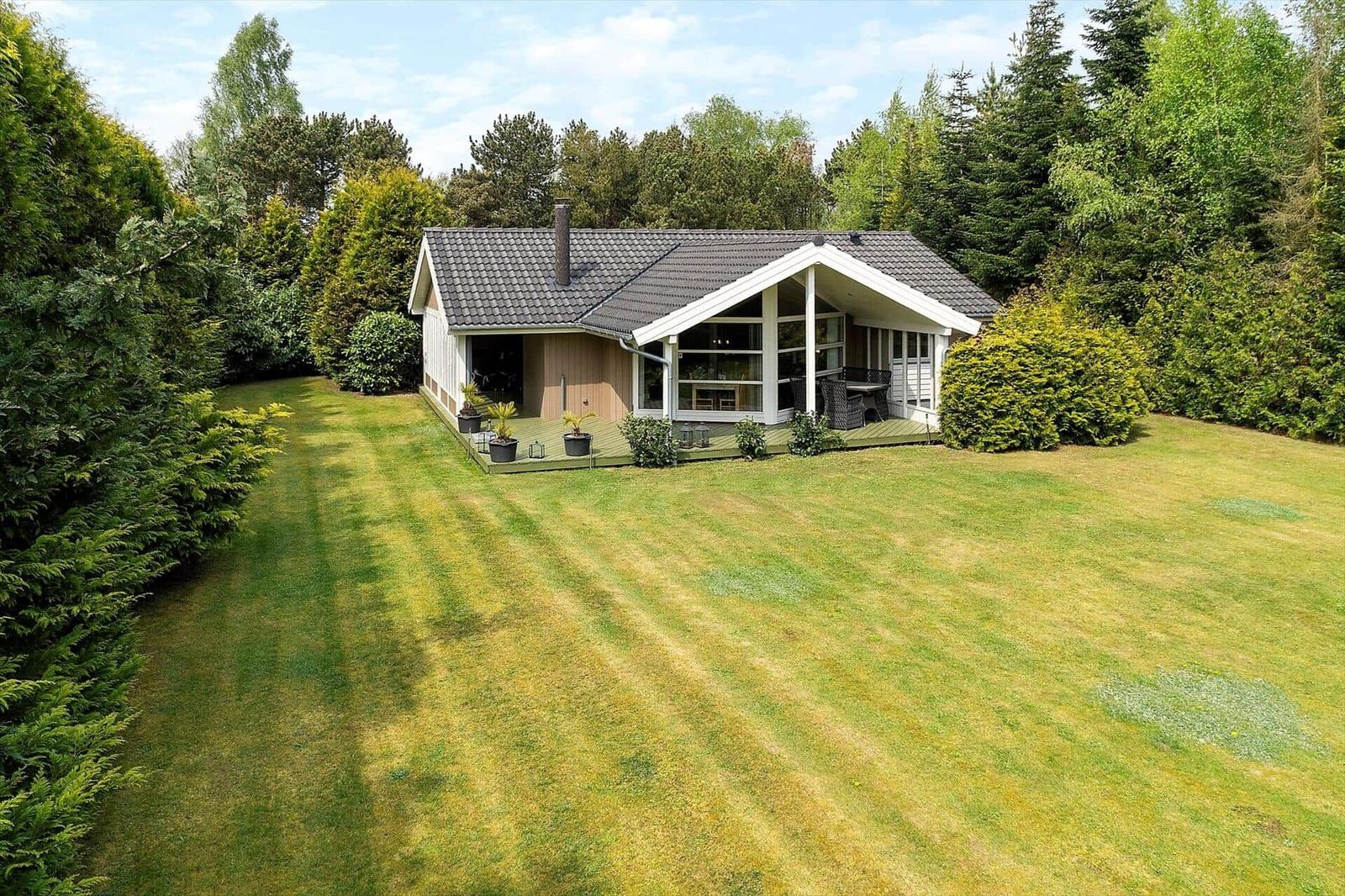 House with large garden and terrace surrounded by trees.