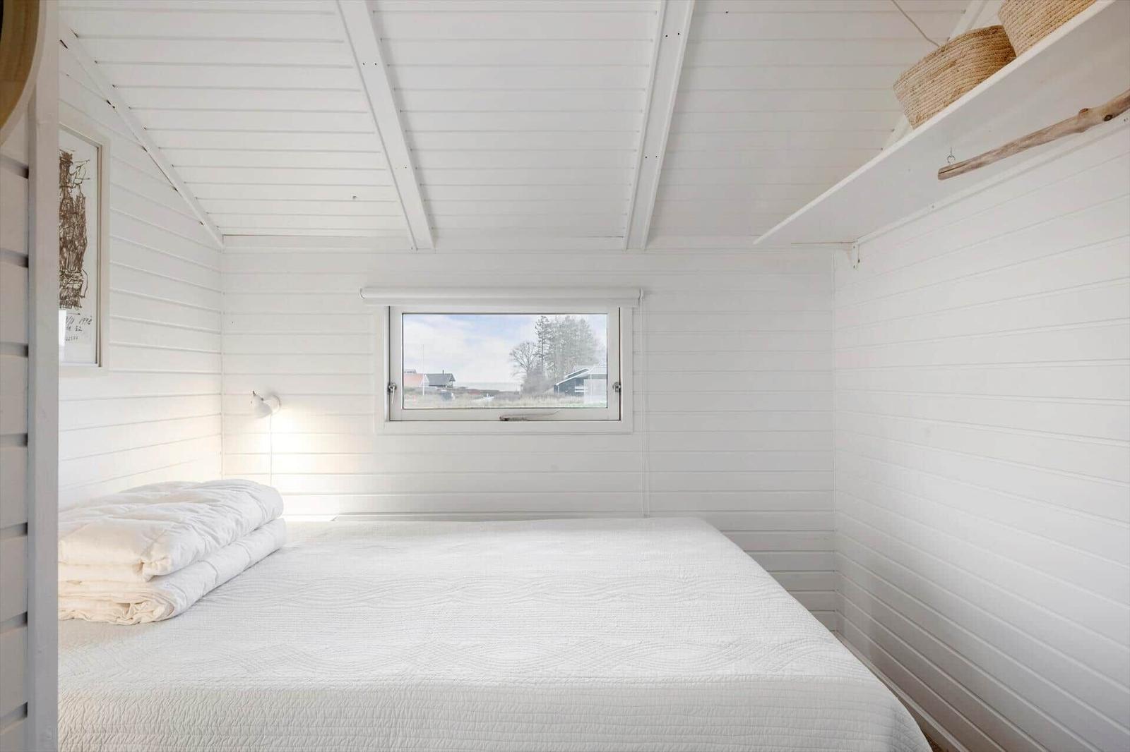 Schlafzimmer mit weißem Bett und Fensterblick