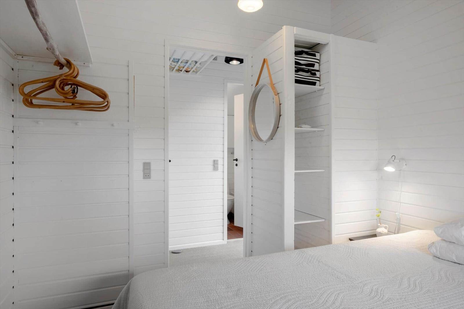 Schlafzimmer mit weißem Holz, Bett, Kleiderschrank und Spiegel.