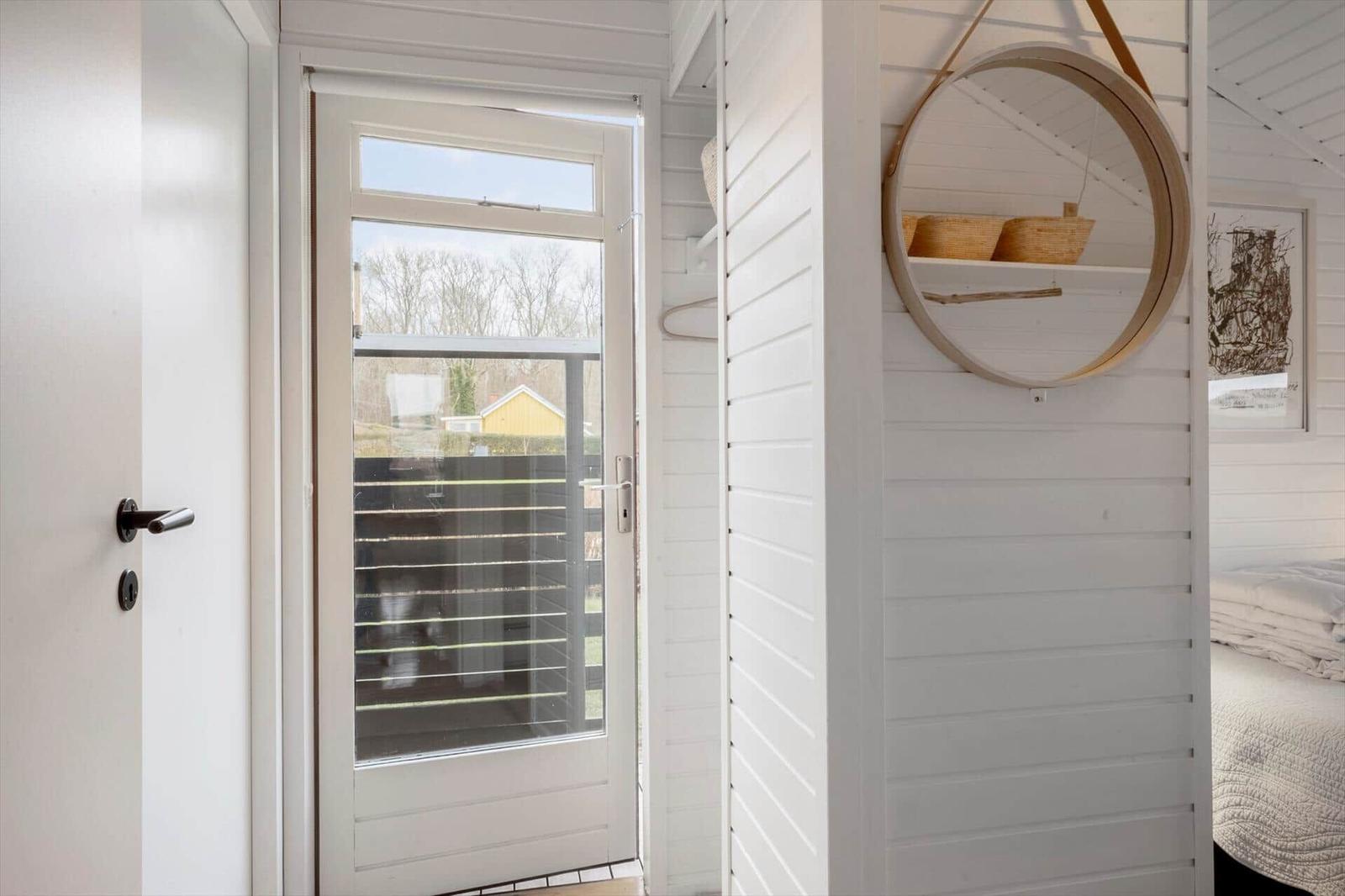 Eingangsbereich mit Tür, Fenster und Spiegel an der Wand.