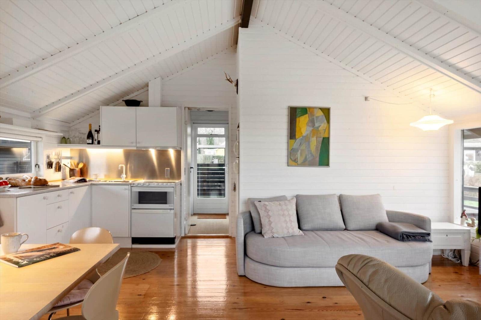 Wohnbereich mit Sofa, Küchenzeile und Holzboden unter weißem Dach