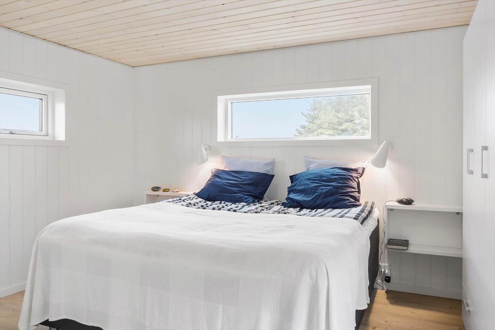 Schlafzimmer mit weißer Wand und Bett mit blauen Kissen.