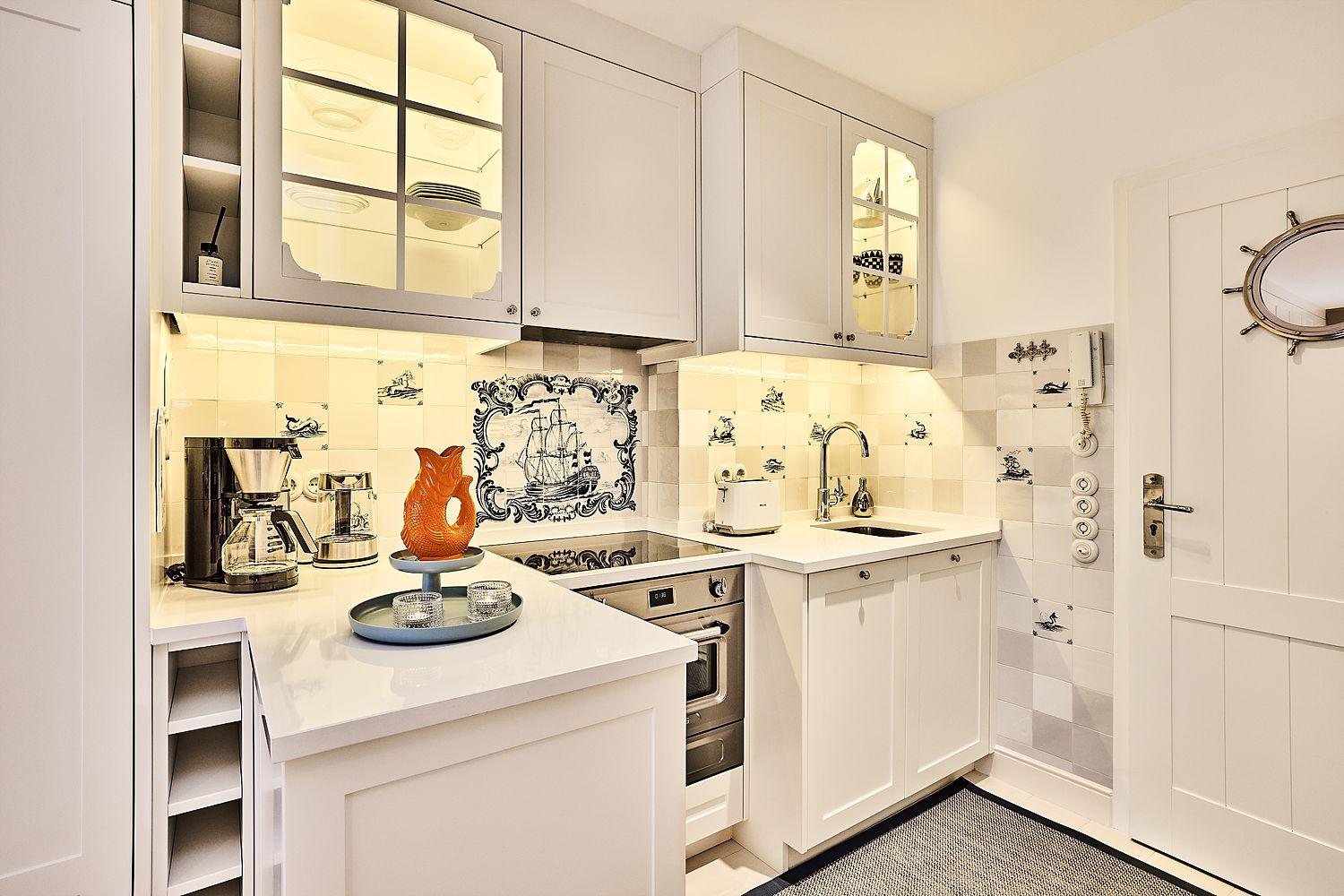 Küche mit weißen Schränken, Backofen und dekorativen Fliesen.
