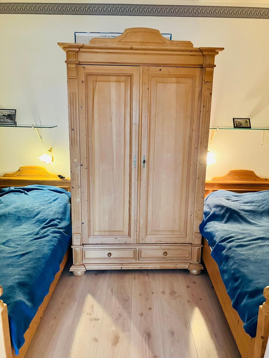 Zwei Betten mit blauen Bettdecken und ein Holzschrank in einem Schlafzimmer.