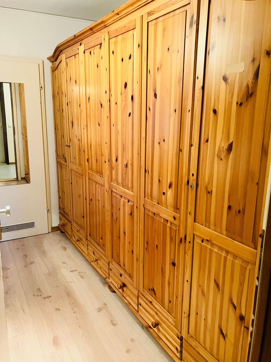 Großer Holzschrank mit mehreren Türen und Schubladen in einem Raum mit Holzboden.