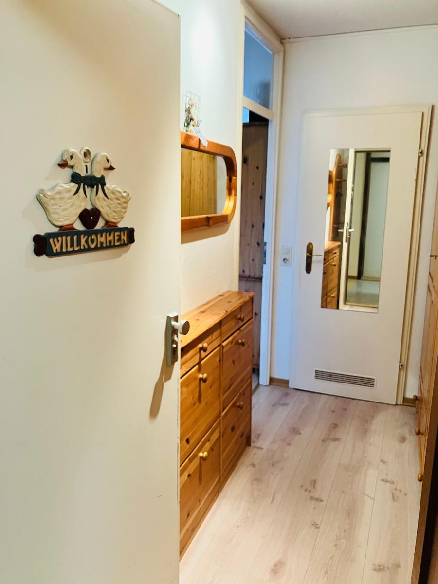 Eingangsbereich mit Holzschrank, Spiegel und Willkommensschild mit Enten.